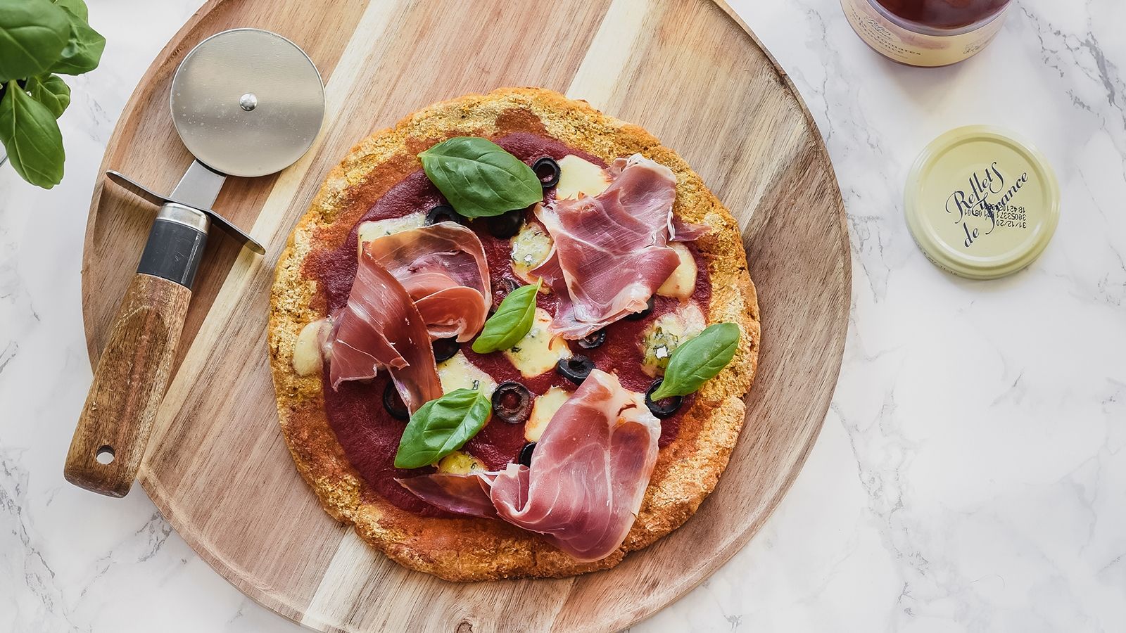 Bezglutenowa pizza na marchewkowym spodzie z szynką serrano, serem pleśniowym i oliwkami
