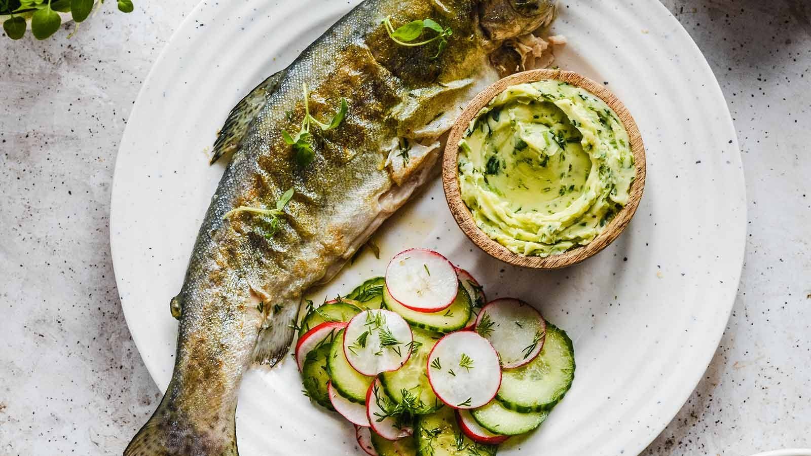 Grillowany pstrąg z masłem pietruszkowym, podany z surówką z ogórka i rzodkiewki
