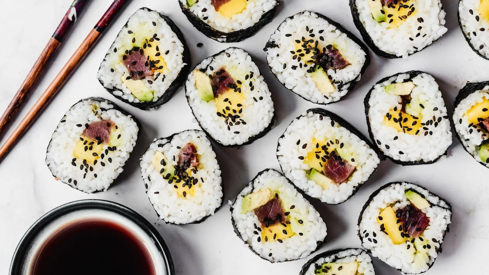 Sushi z tuńczykiem, mango i awokado posypane czarnym sezamem
